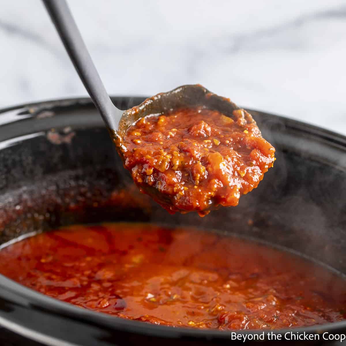 A ladle filled with crock pot spaghetti sauce.