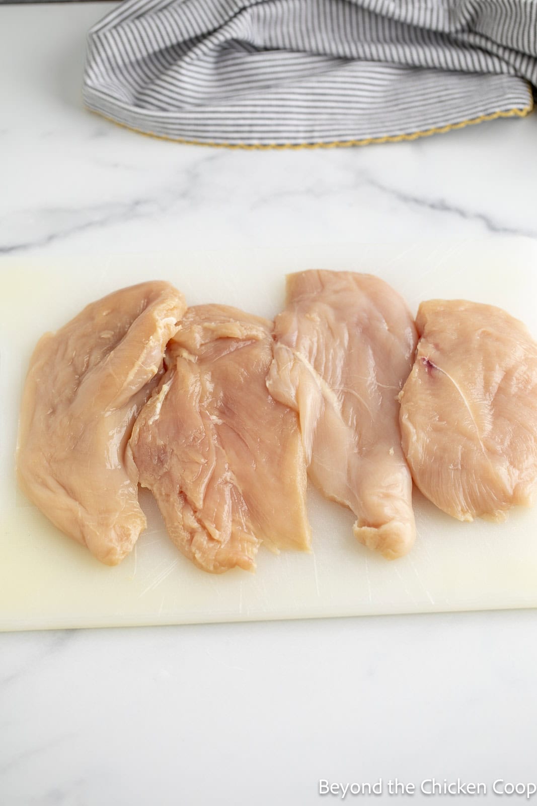 Chicken cutlets on a cutting board.