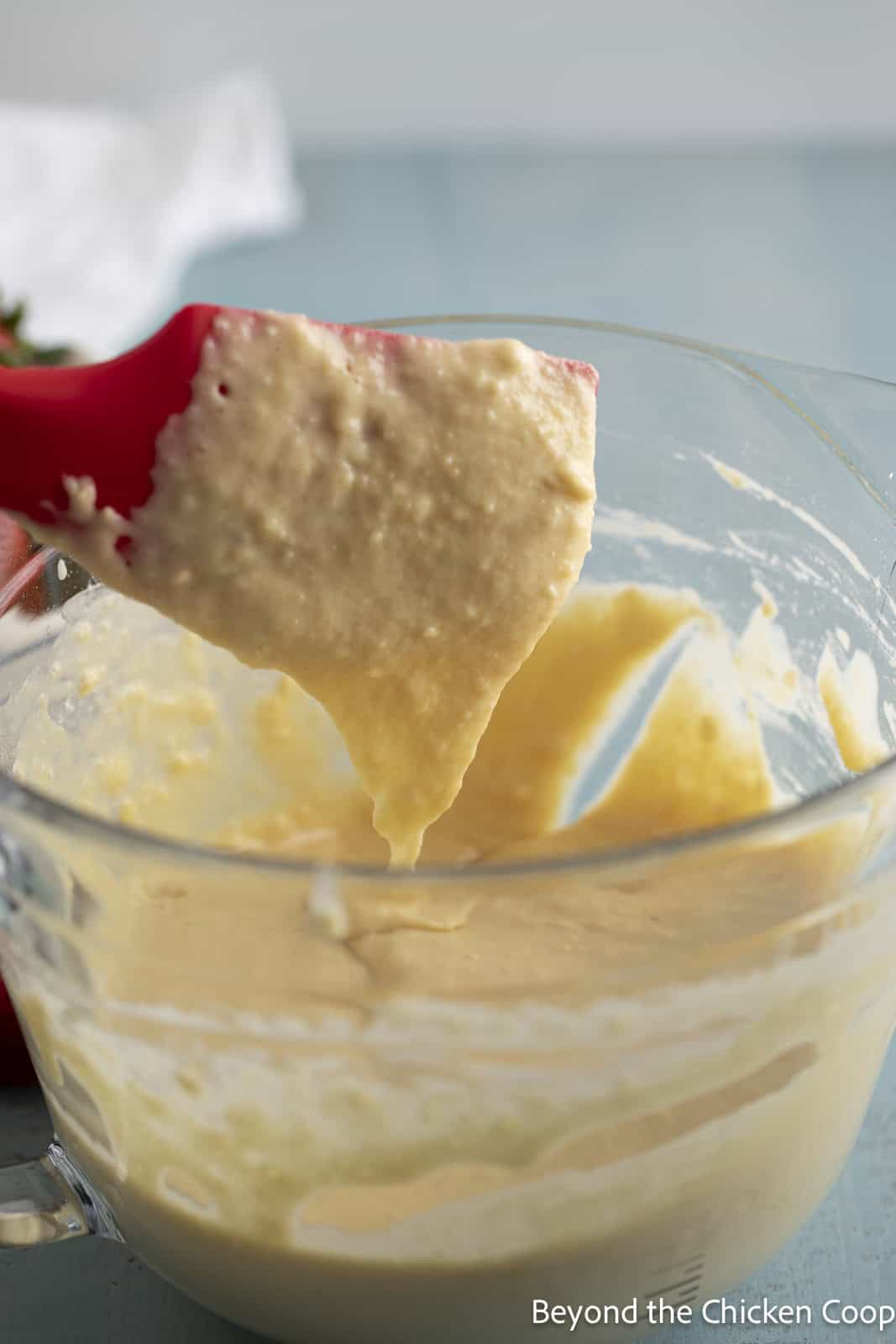 Pancake batter dripping of a red spatula. 