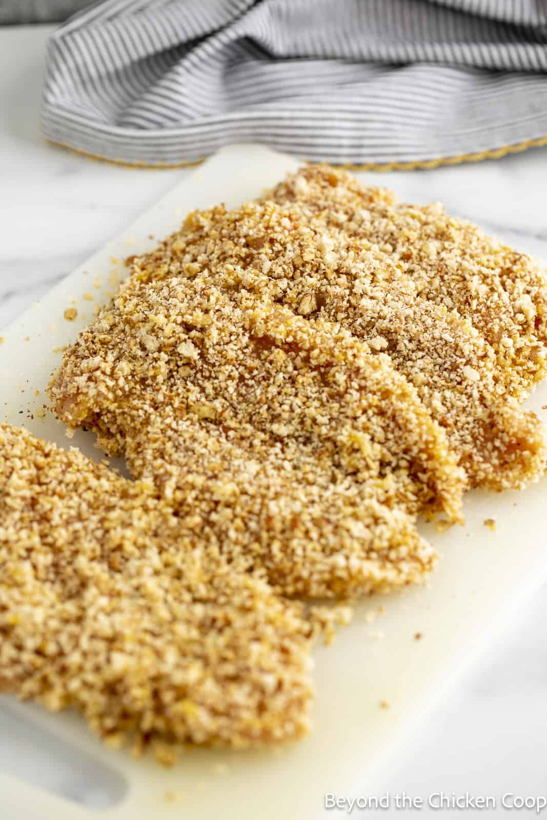 Breaded chicken breasts on a cutting board.