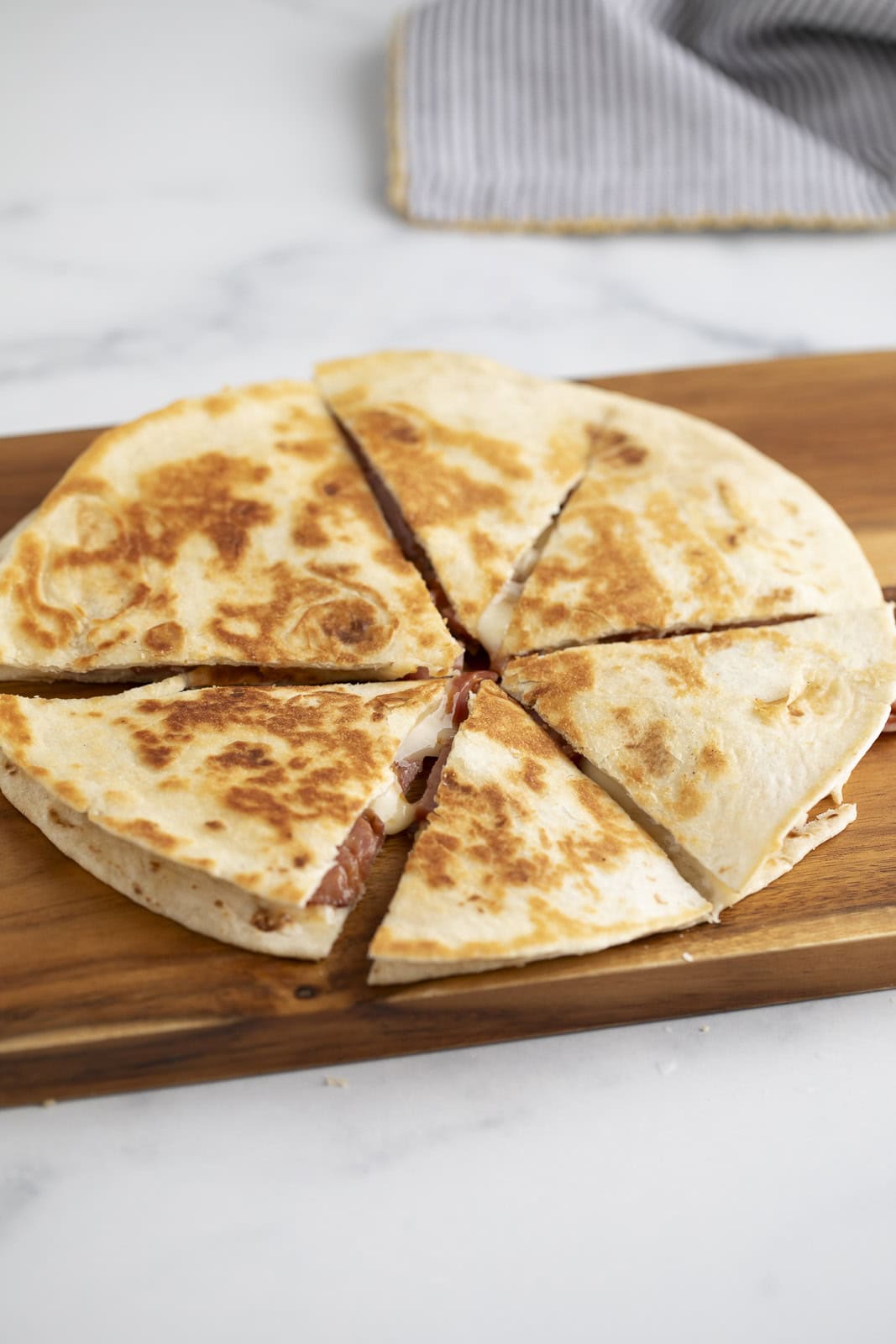 A sliced quesadilla on a wooden board. 