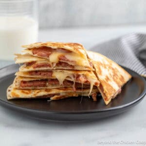 Smoked sausage quesadilla on a black plate.