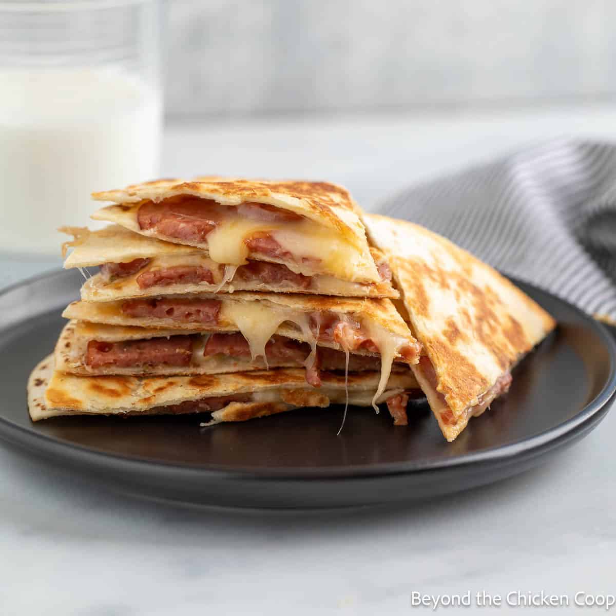 Smoked sausage quesadilla on a black plate.