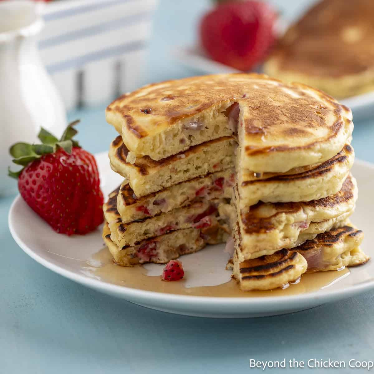 A stack of strawberry pancakes on a white plate.