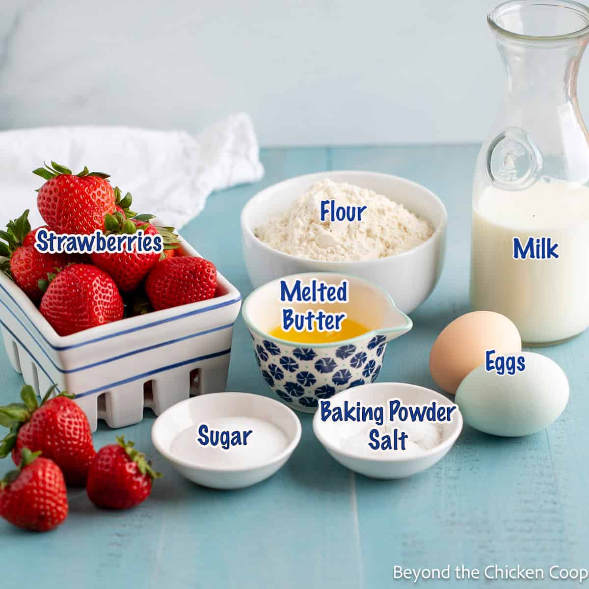 Small bowls filled with flour, butter, sugar, along with other ingredients for making pancakes. 
