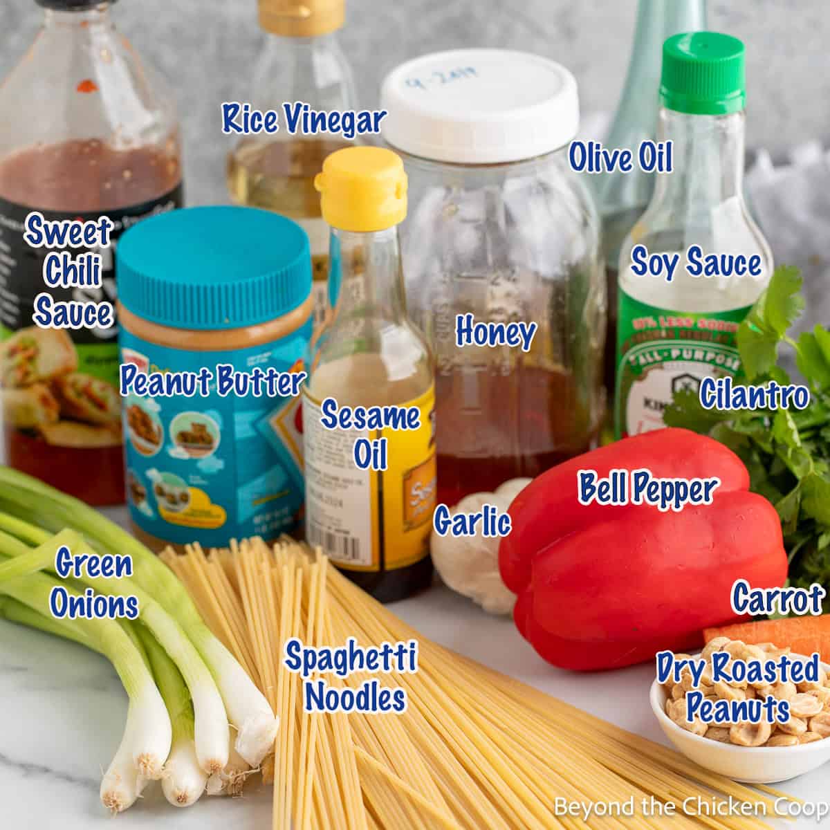 Jars of condiments, peanut butter, and fresh veggies on a countertop.
