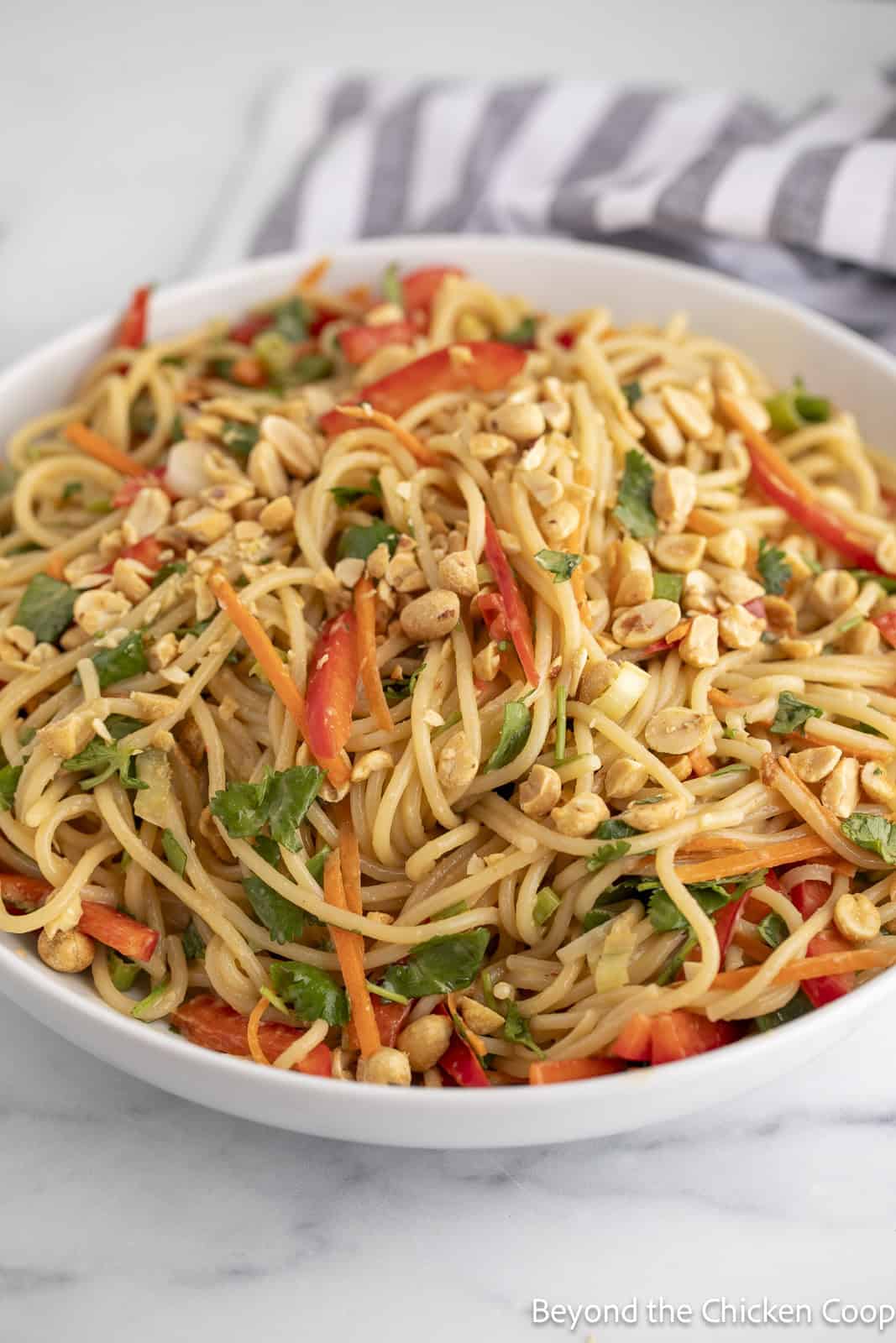 Noodle salad with bell peppers, carrots, and cilantro in a glass bowl.