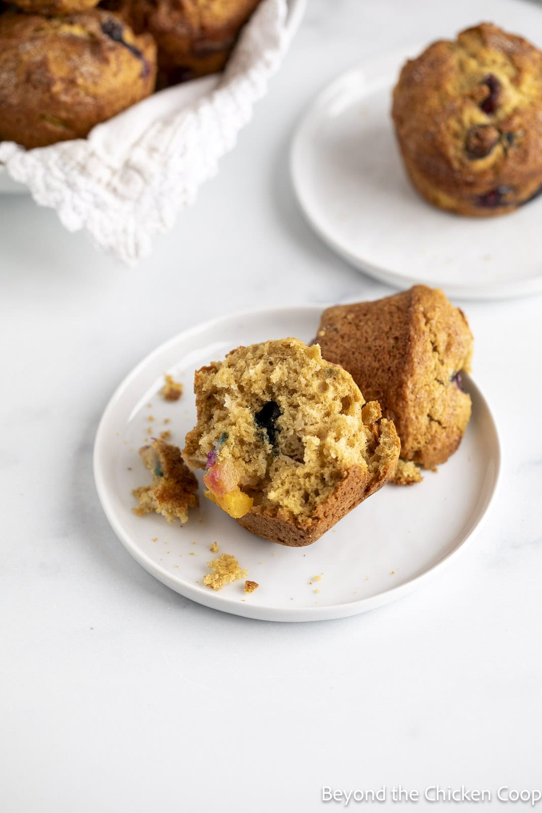 A muffin filled with blueberries and peaches on a white plate.