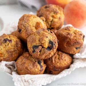 A basket filled with blueberry peach muffins.