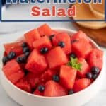 Watermelon and blueberries with mint in a white bowl.