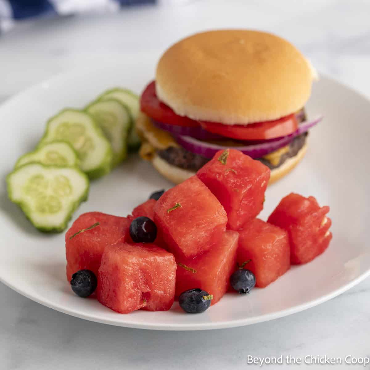 Watermelon salad on a plate with a hamburger. 