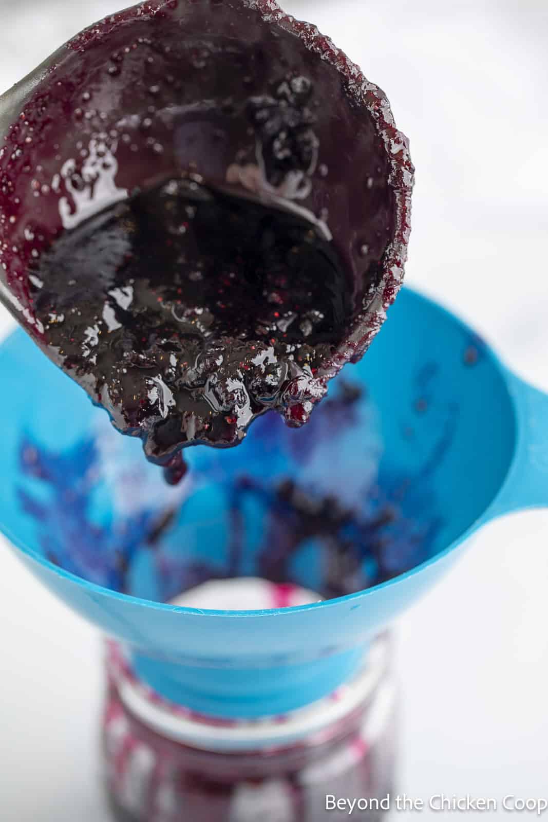 Pouring homemade jam into a canning jar.