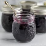 A jar of homemade blueberry jam with a spoon.