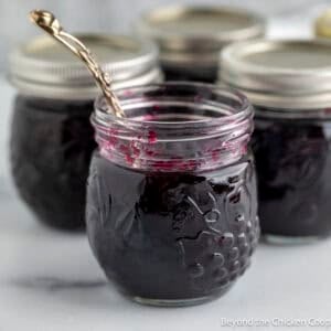 A jar of homemade blueberry jam with a spoon.