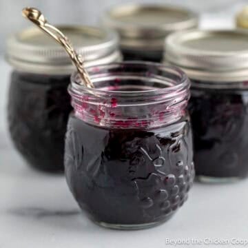 A jar of homemade blueberry jam with a spoon.
