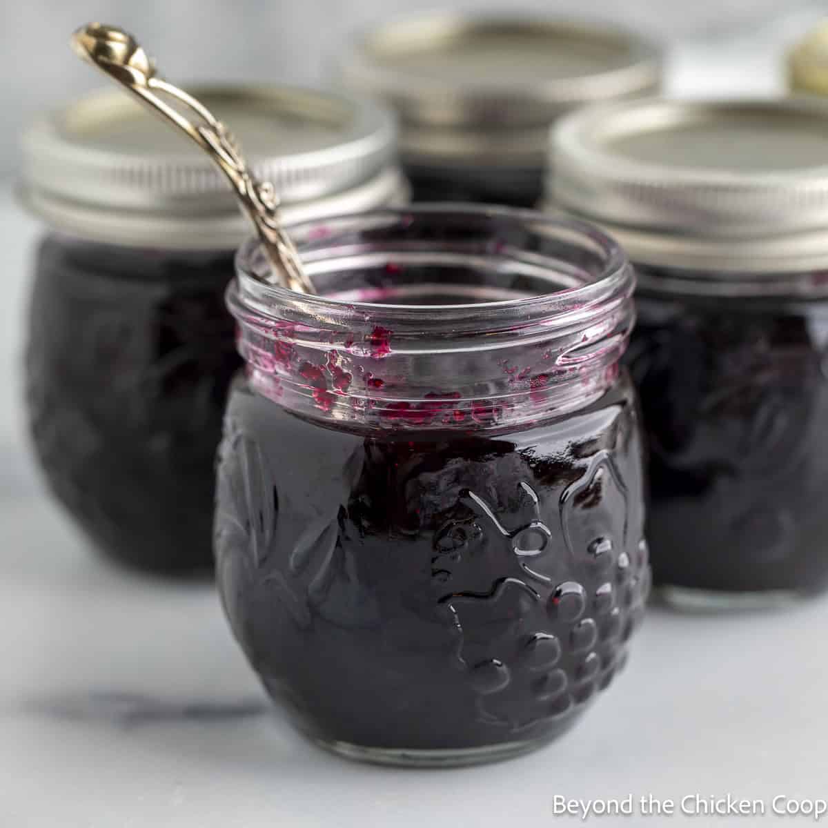 A jar of homemade blueberry jam with a spoon.