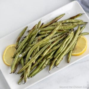 Oven Roasted Green Beans on a white platter with lemon slices.