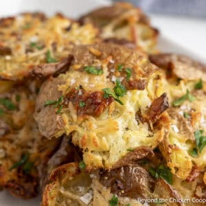 Parmesan smashed potatoes piled on a white plate.