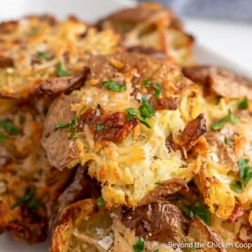 Parmesan smashed potatoes piled on a white plate.