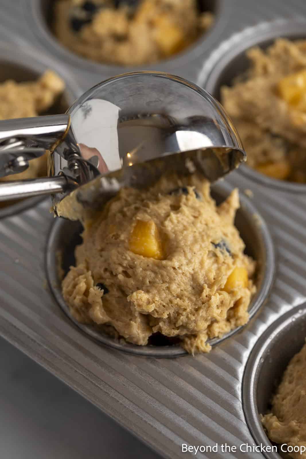 Scooping muffin batter into a tin.