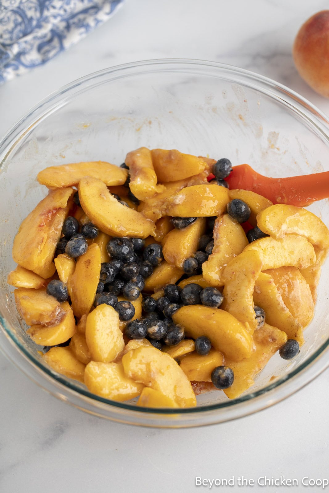 Sliced peaches and blueberries in a glass mixing bowl. 