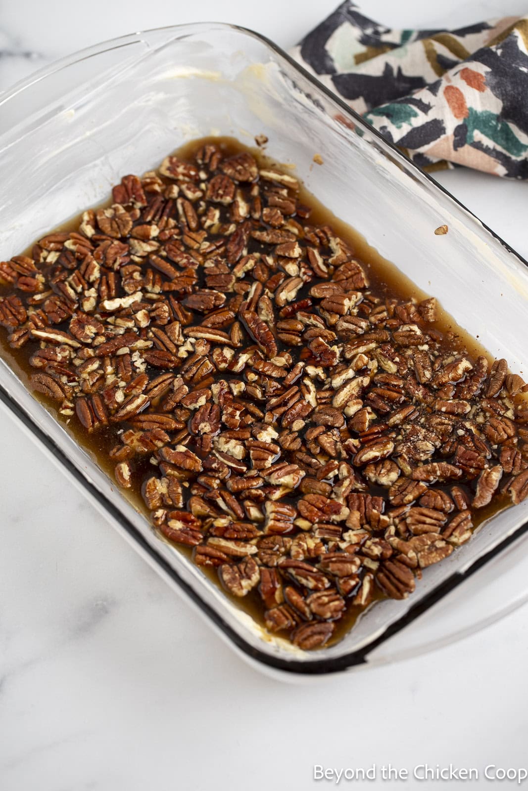 Pecans and sauce in the bottom of a casserole dish. 