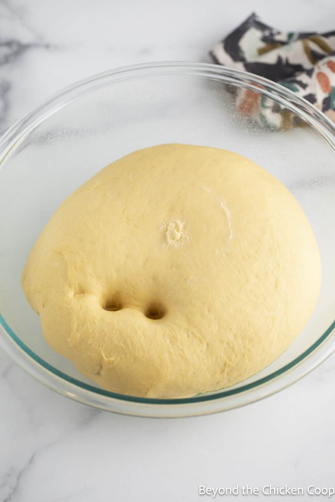 Risen bread dough in a glass bowl. 