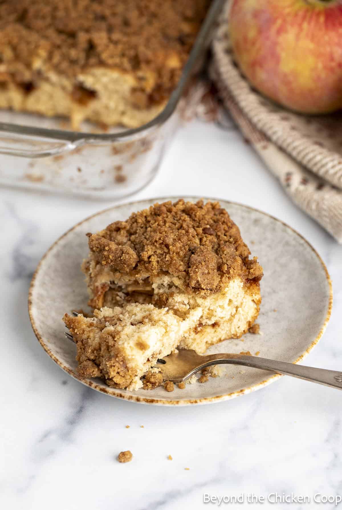 A bite of coffee cake with apples and cinnamon on a fork. 