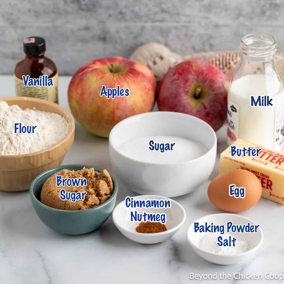 Fresh apples, bowls of sugar and flour, and small bowls with spices. 