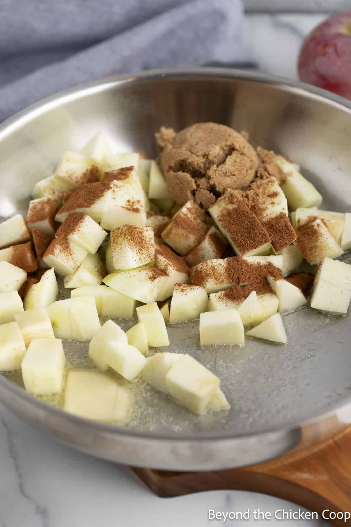 Cubed apples in a skillet with brown sugar and spices.