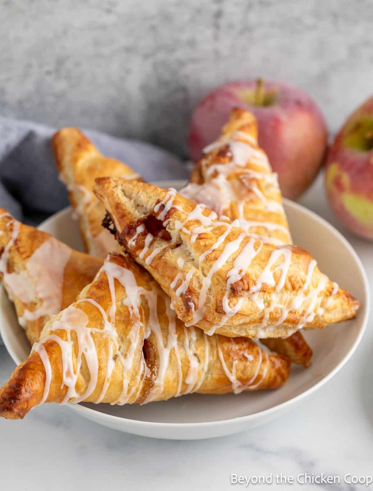 Apple hand pies piled in a white bowl.