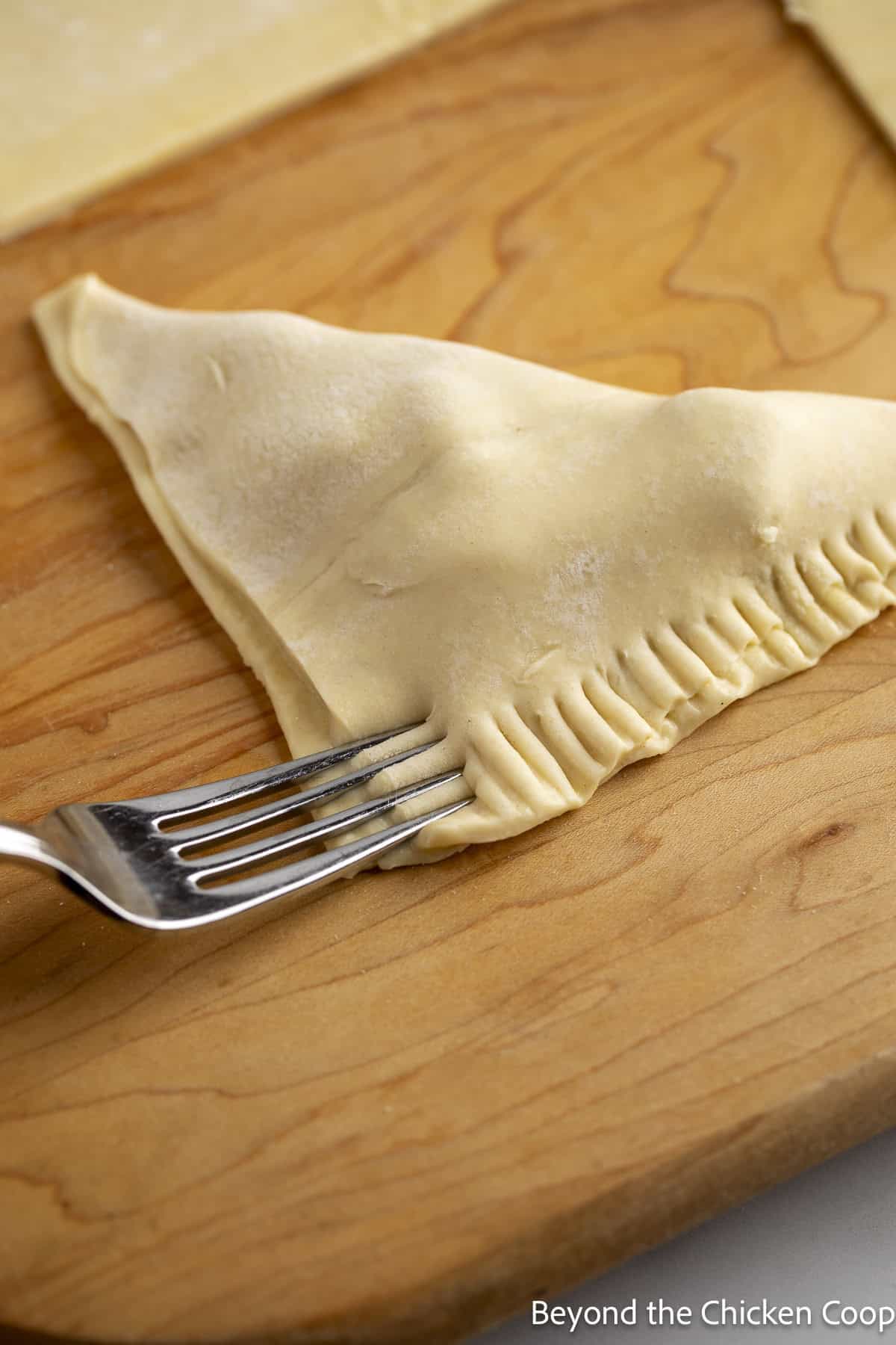 Crimping the edges of a mini pie with a fork.
