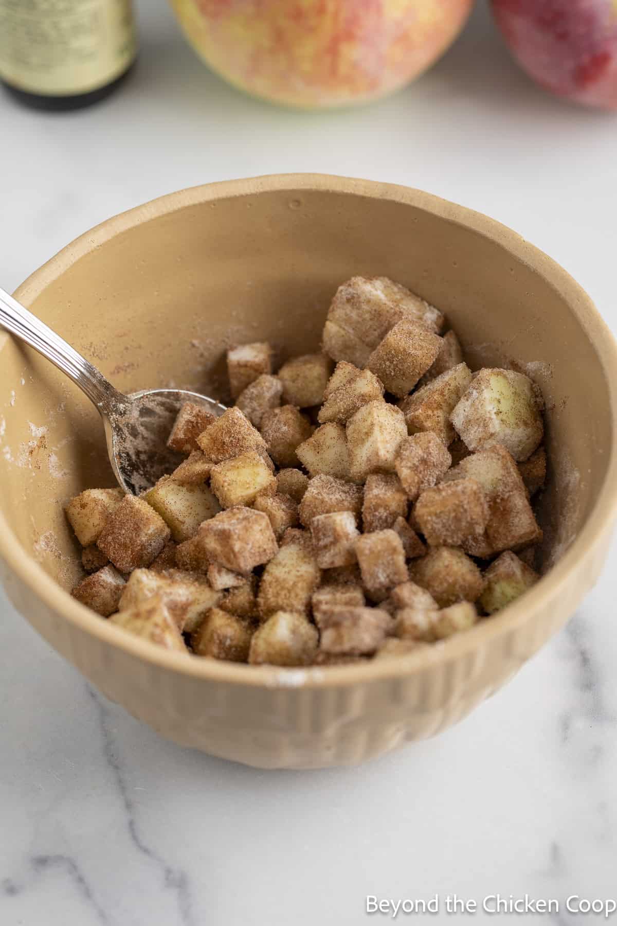 Diced apples covered with sugar and cinnamon in a bowl. 
