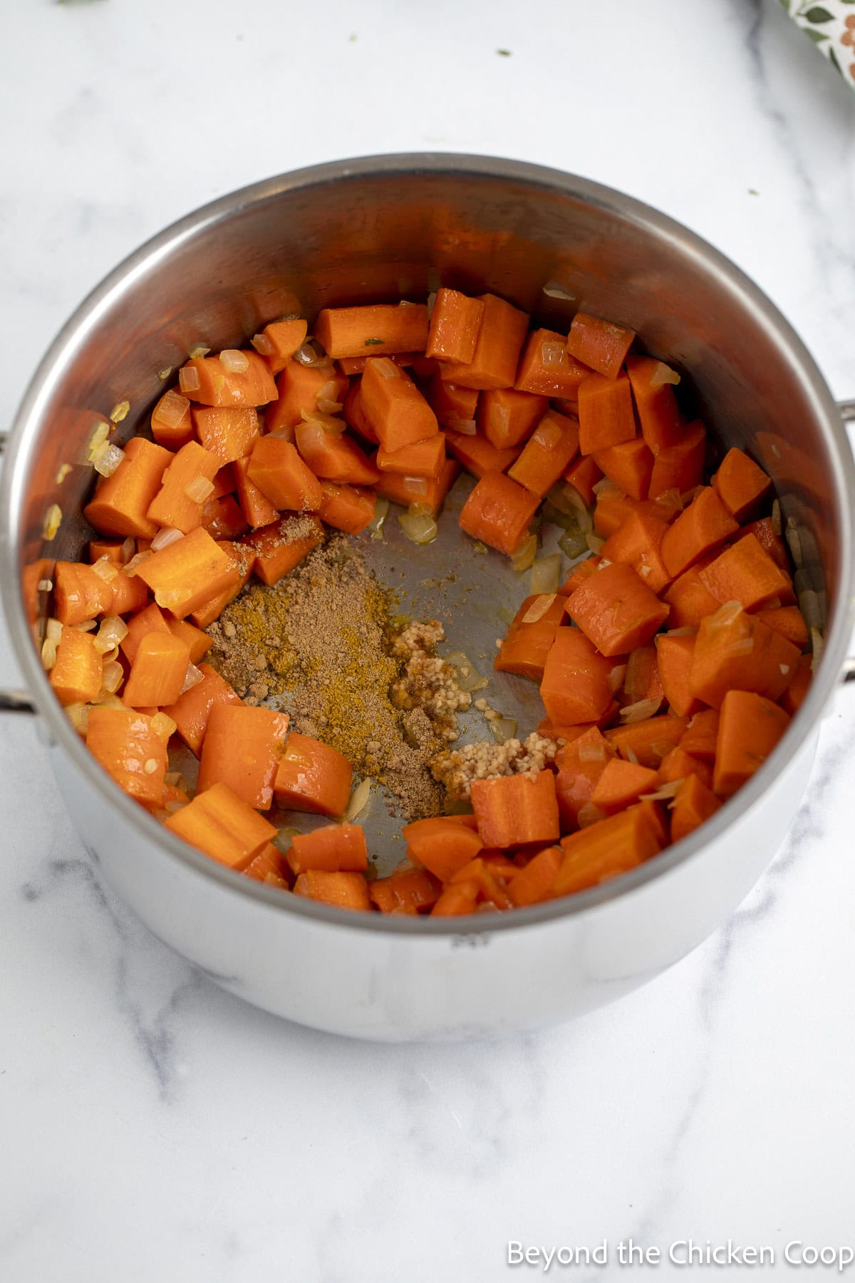 Adding spices to a pot with chopped carrots.