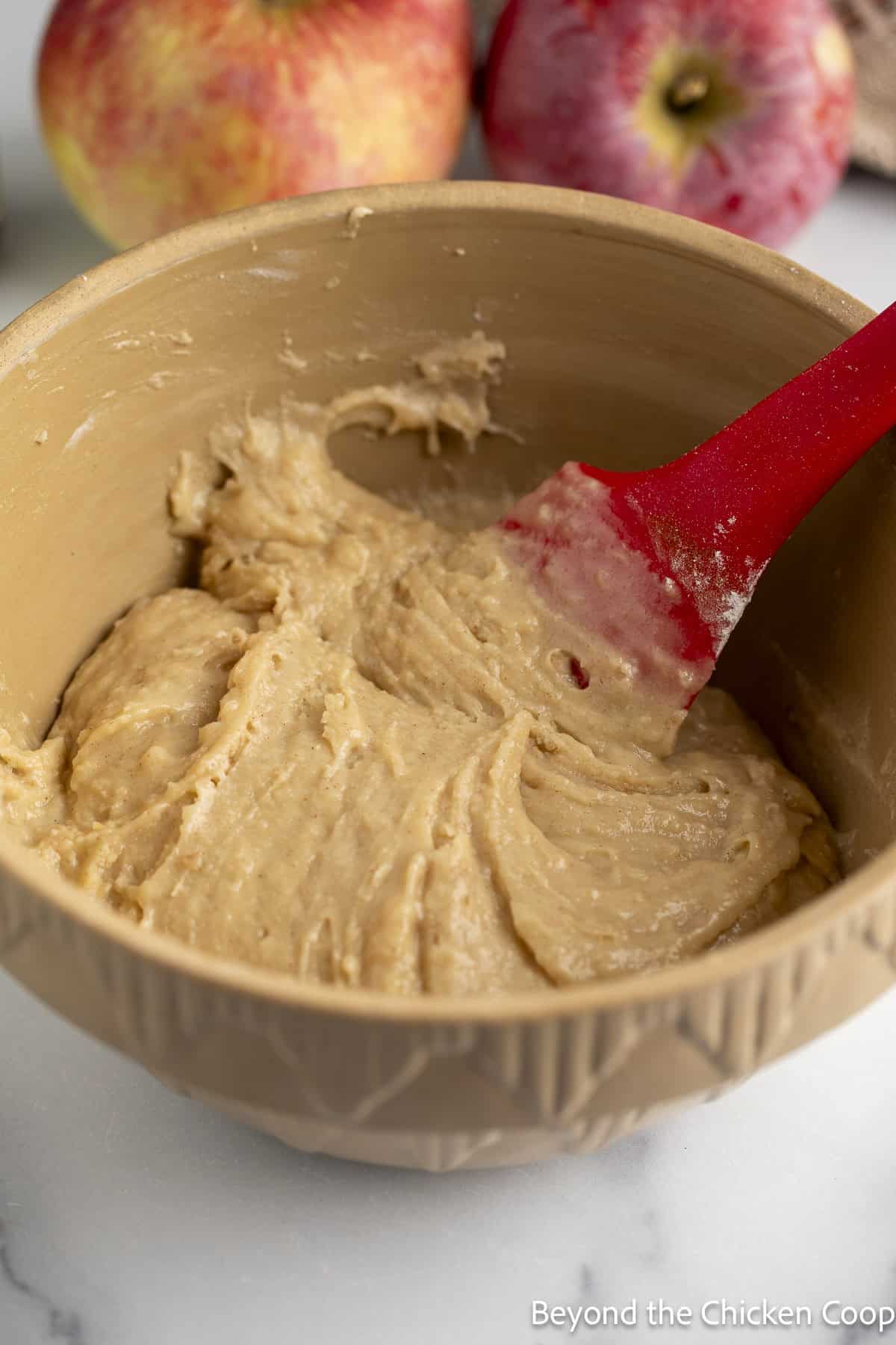 Cake batter in a bowl with a red spatula. 