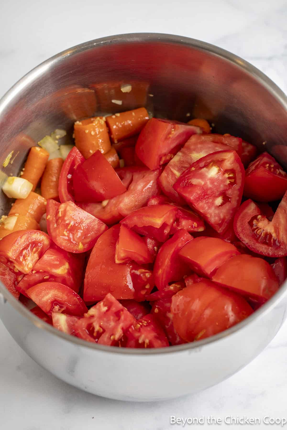 Fresh tomato chunks added to a soup pot. 