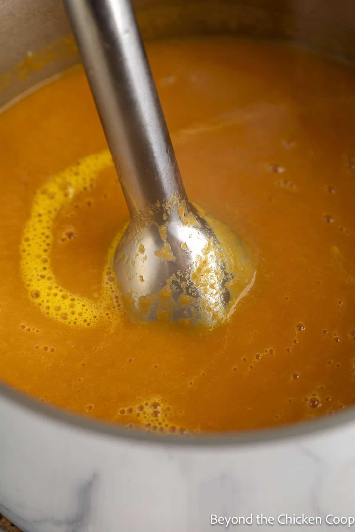 Pureeing carrot soup with an immersion blender.