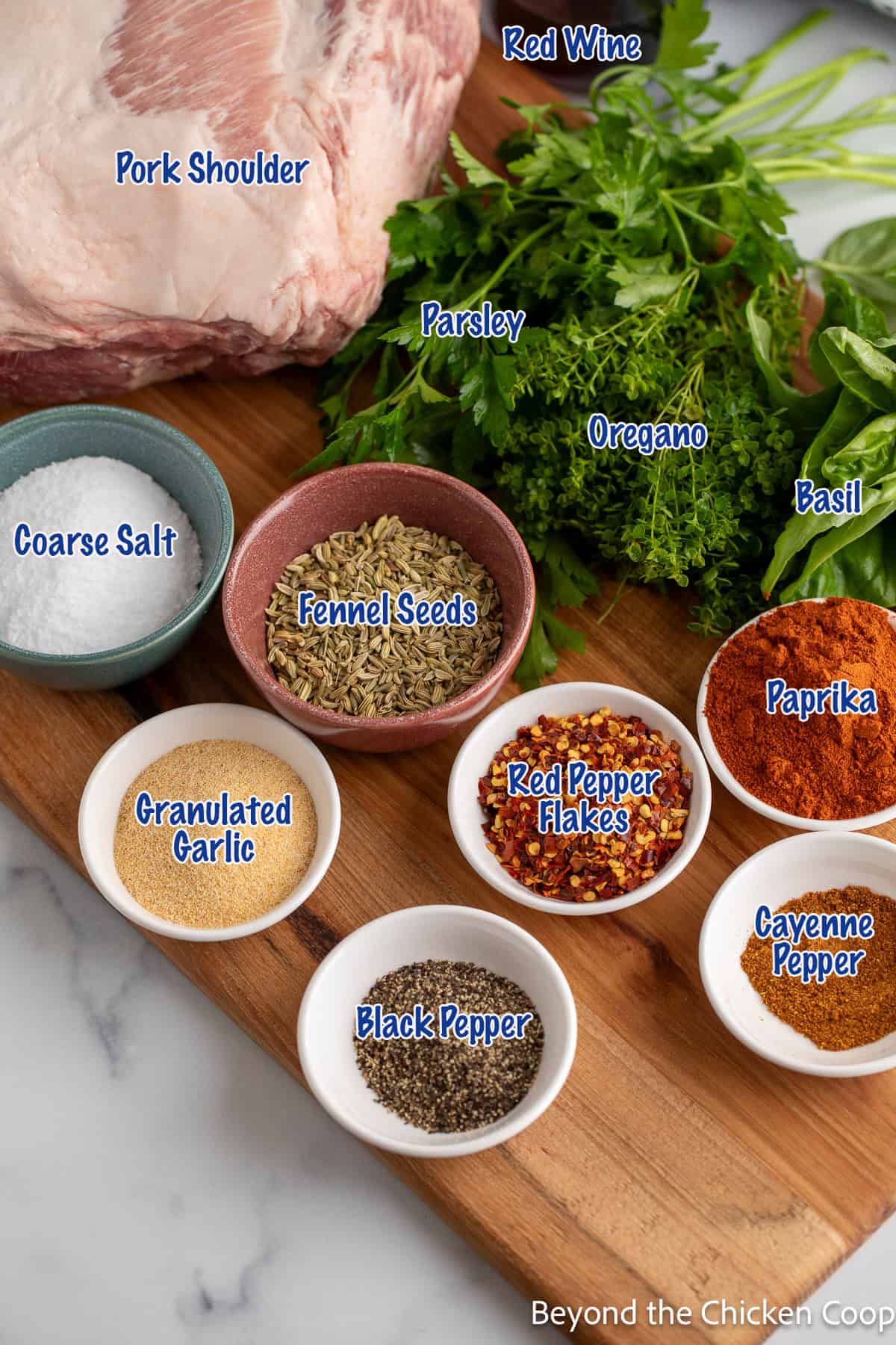 Spices, herbs, and a pork roast on a wooden board. 