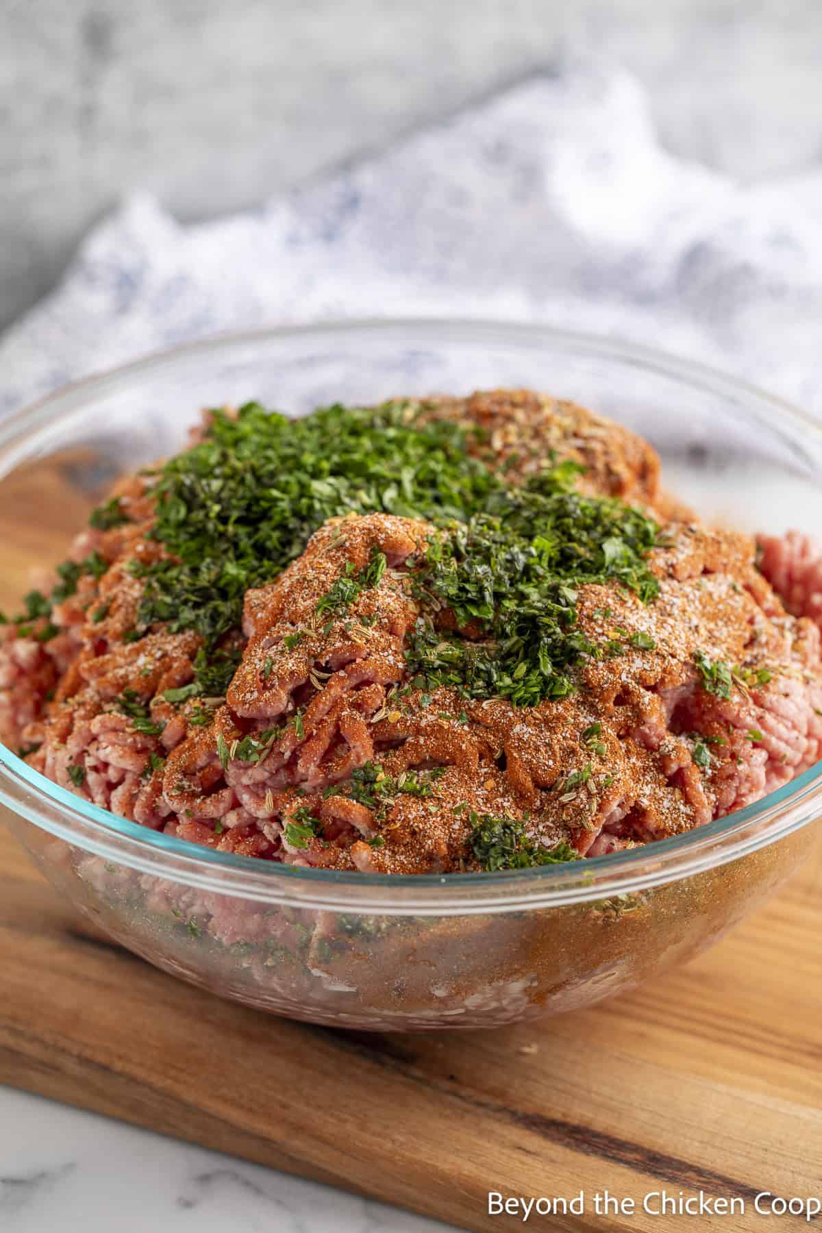 Adding fresh herbs and spices to ground pork. 