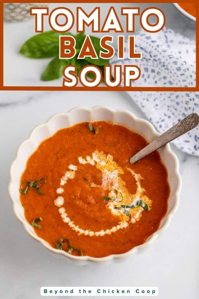 A bowl of tomato soup topped with fresh herbs and a drizzle of cream.