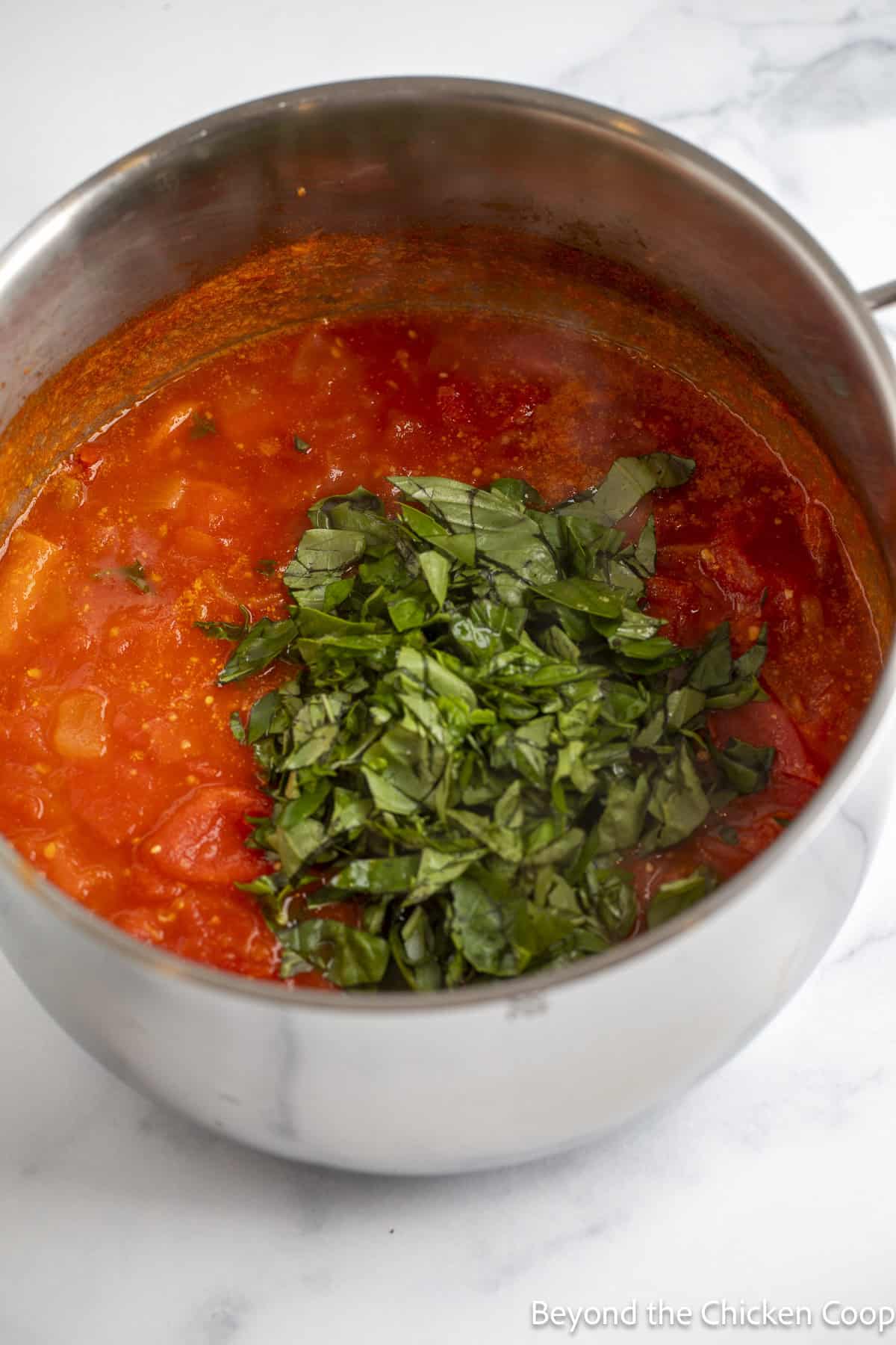 Tomato soup topped with fresh basil in a large pot. 