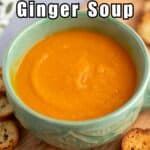 A green mug filled with carrot soup.