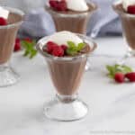 A glass parfait filled with chocolate pudding and whipped cream.