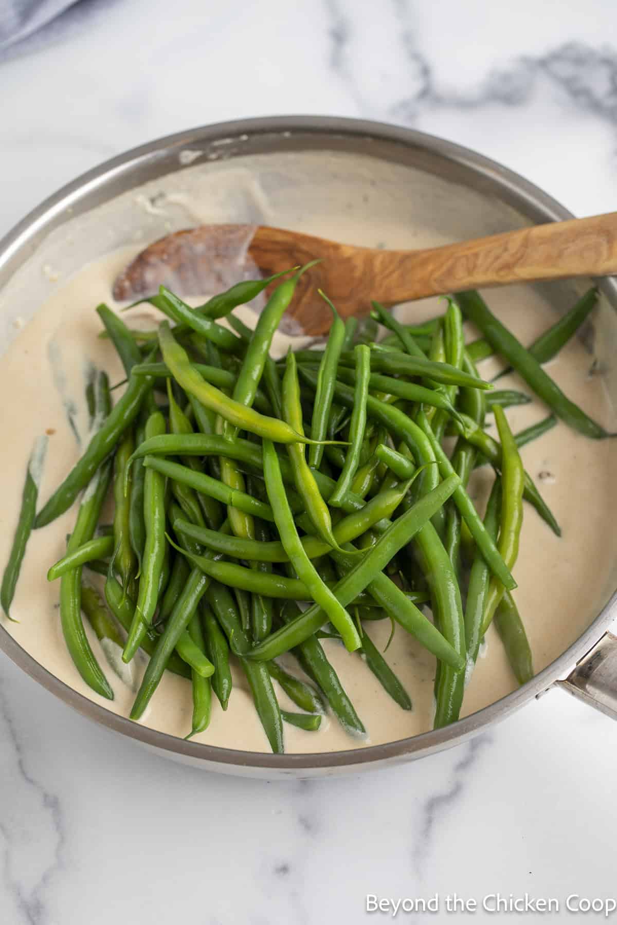 Adding blanched green beans to a white sauce.