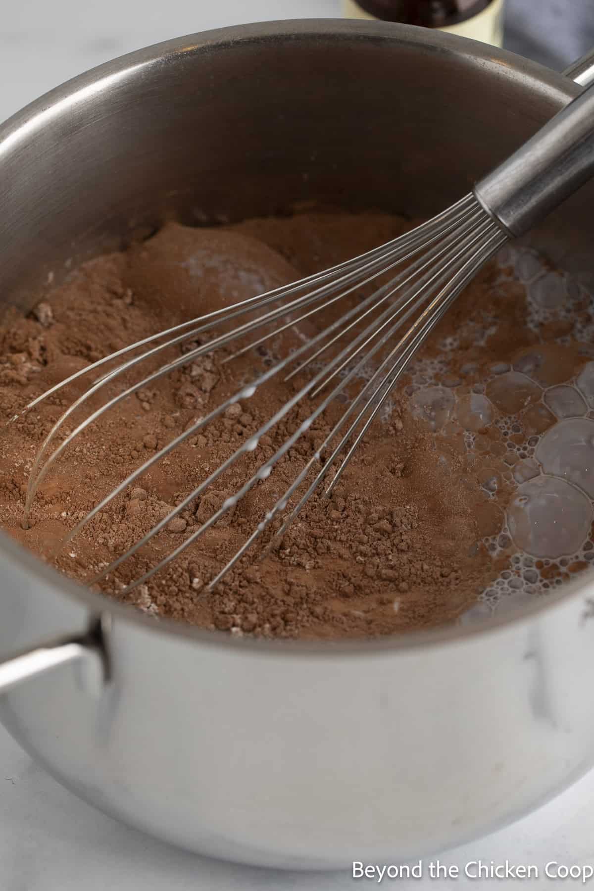 Whisking together pudding ingredients in a saucepan. 