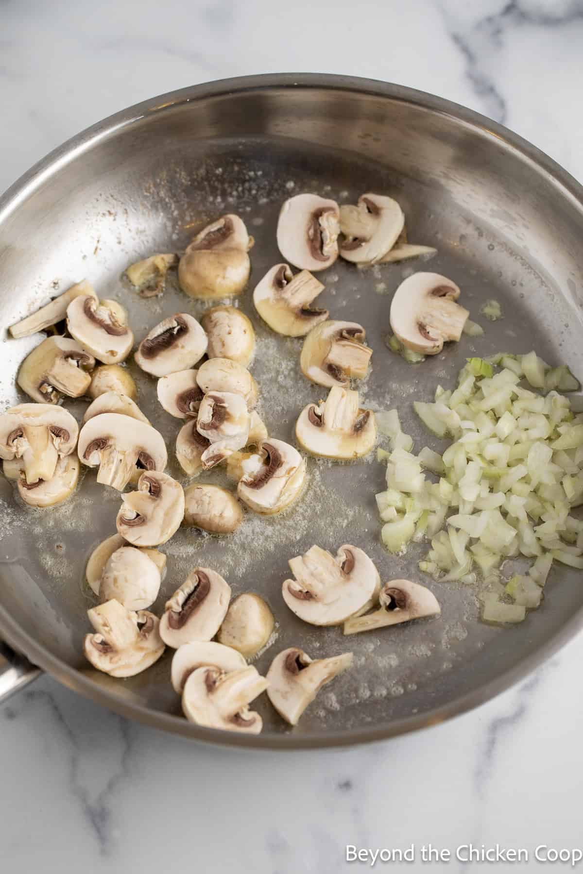 Mushrooms and onions in a sauté pan.