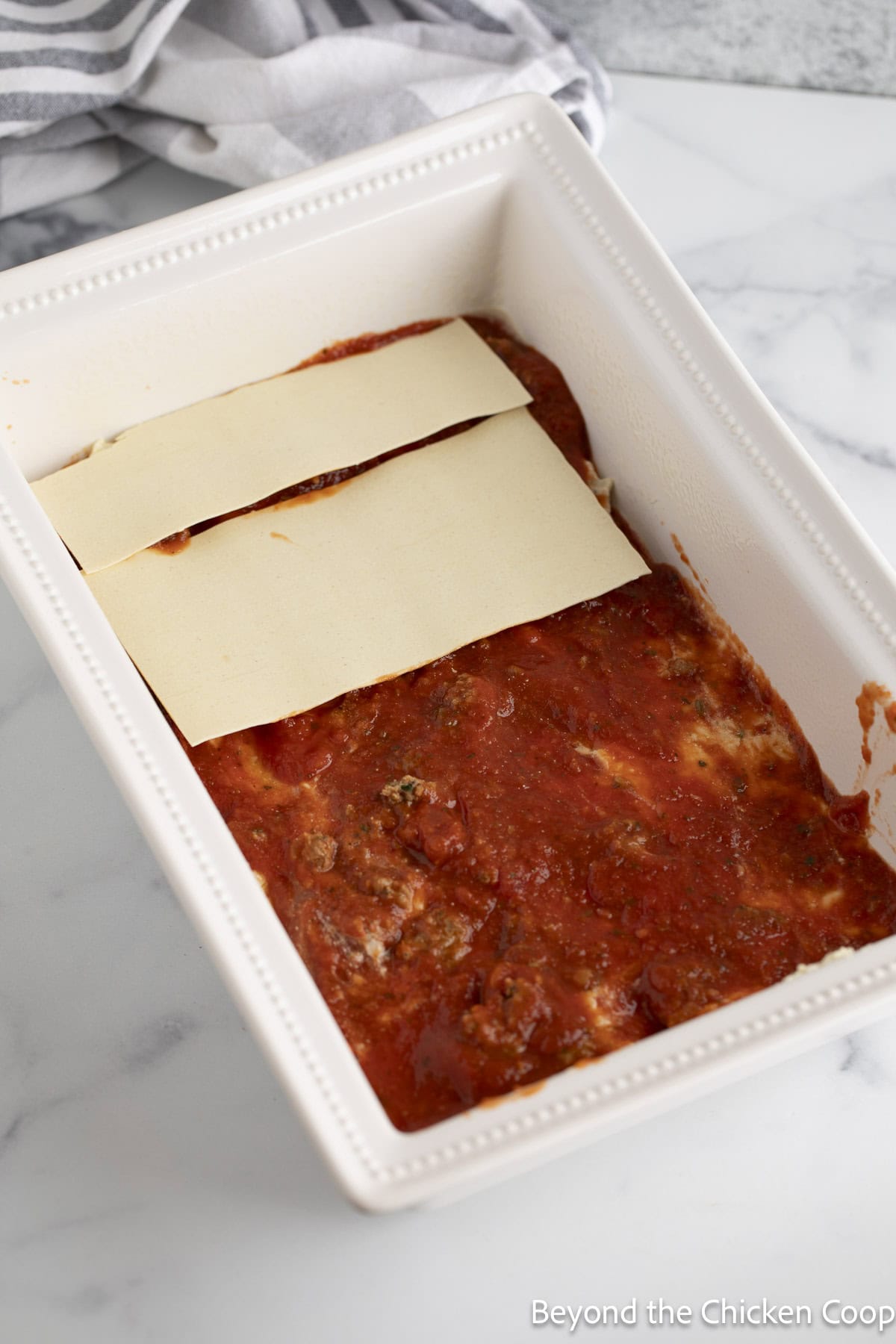 Adding no-boil noodles to a lasagna. 