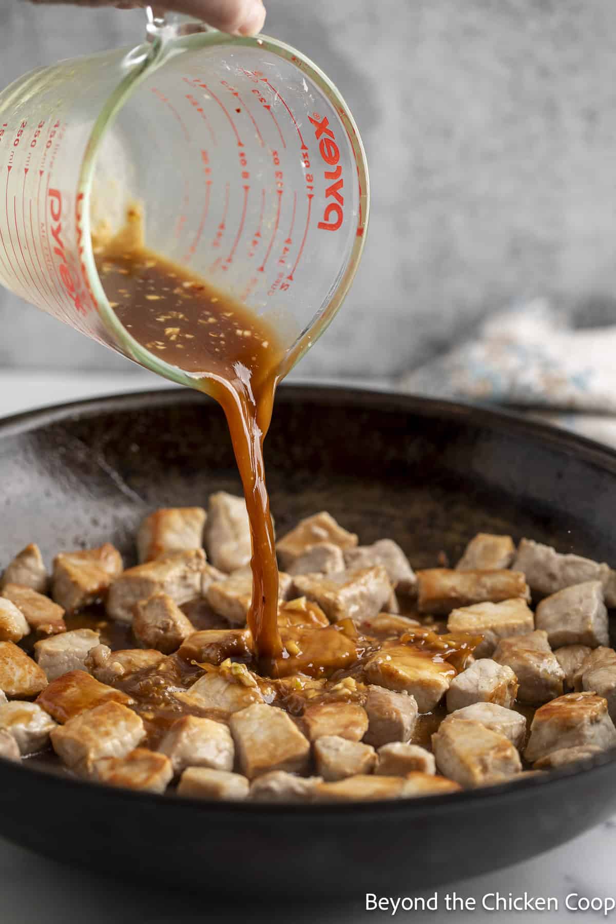 Pouring a brown sauce over cooked pork.