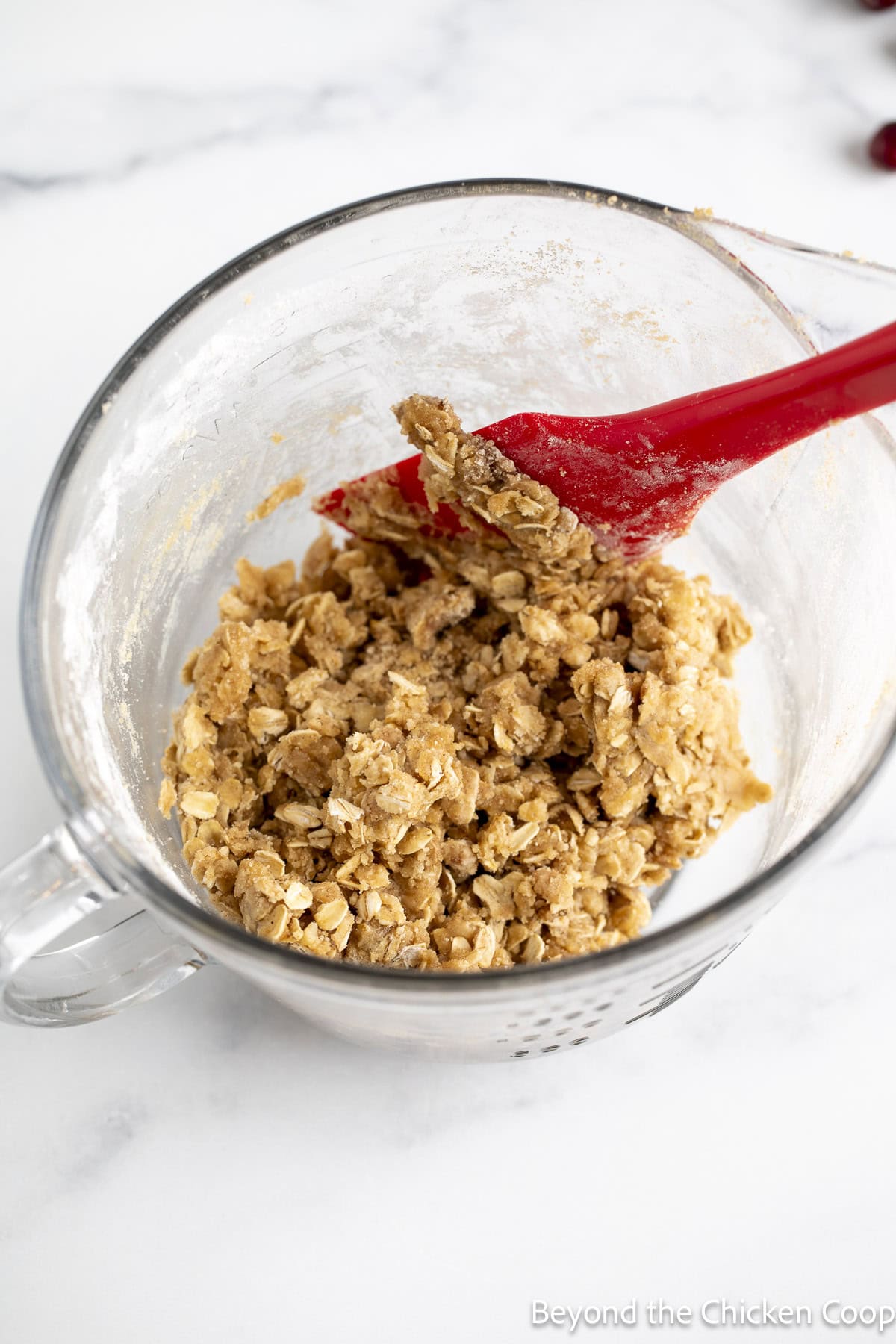 An oatmeal topping combined together in a glass mixing bowl.