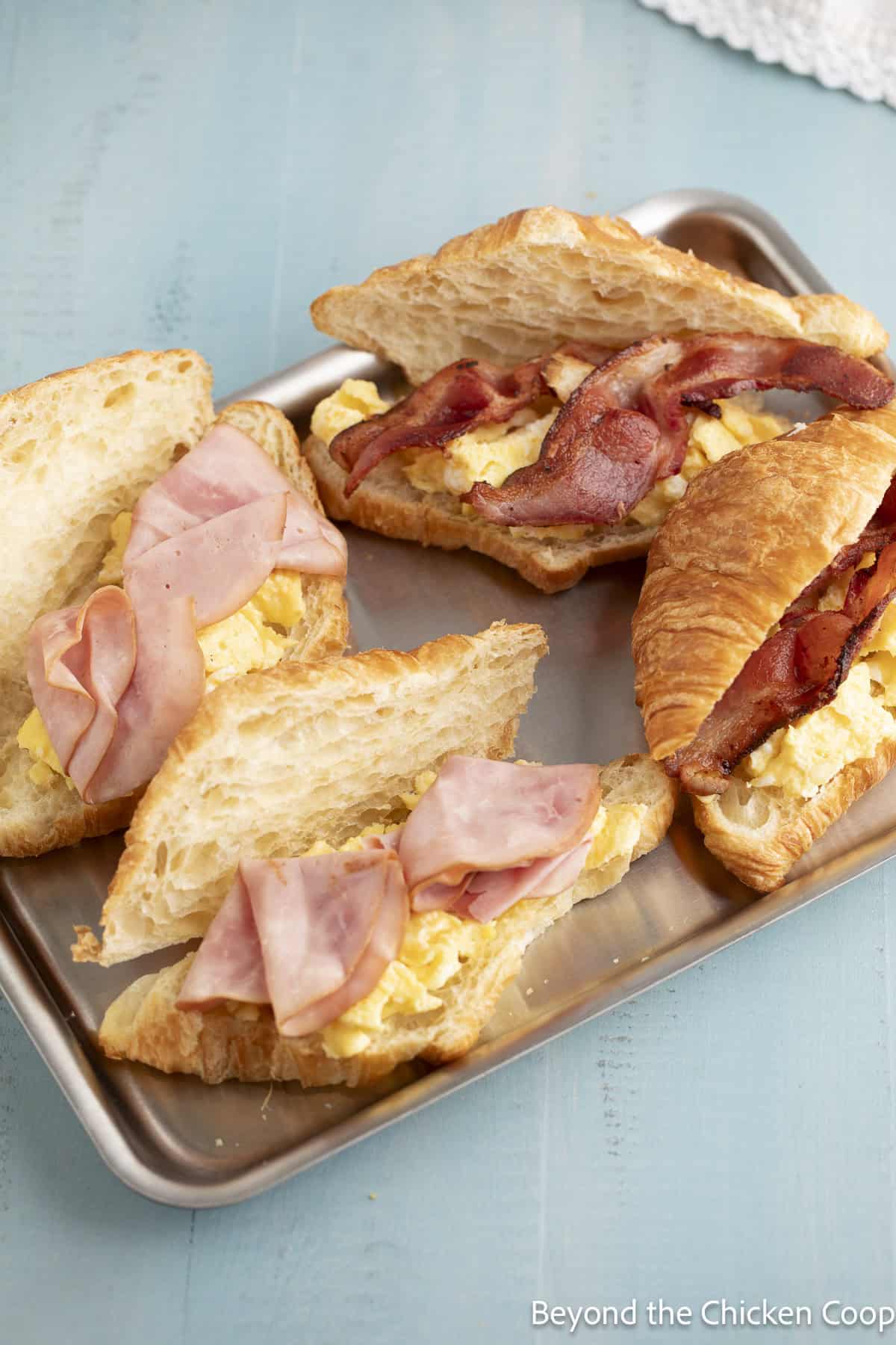 Sliced ham and crispy bacon layered on a croissant.